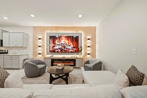 Ein modernes Wohnzimmer mit Fernseher, Kamin und einer gemütlichen Sitzecke.