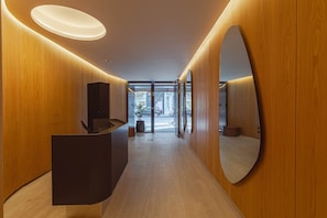 A modern reception area with wooden paneling, a reception desk, and a large mirror. - MOT Rentals + Design SohoHaus '308' - 3 pax Full Amenities (Buenos Aires)