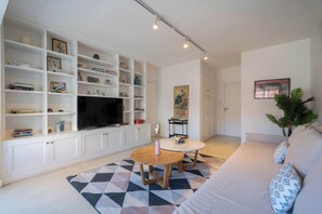 A modern living room with a white sofa, a coffee table, and a TV on a white cabinet. - MOT Rentals + Pacheco de Melo - Stylished Terraced Apt in Recoleta (Buenos Aires)