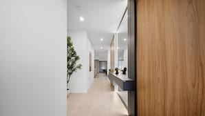 A modern hallway with a wooden accent wall, a potted plant, and a long counter with a mirror. - 6BR house sleeps 12 with spa and pool table (Kissimmee)