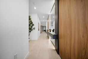 Ein moderner Flur mit einer Wand in Holzoptik, einer Zimmerpflanze und einer langen Theke mit Spiegel.
