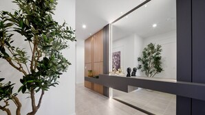 A modern interior with a large mirror reflecting a room, a potted plant, and a wooden cabinet. - 6BR house sleeps 12 with spa and pool table (Kissimmee)