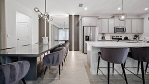A modern kitchen with a central island, bar stools, and stainless steel appliances. - 6BR house sleeps 12 with spa and pool table (Kissimmee)