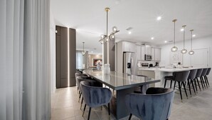 A modern kitchen with a central island, bar stools, and pendant lighting. - 6BR house sleeps 12 with spa and pool table (Kissimmee)