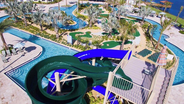 Ein Resort mit einer großen Wasserrutsche, mehreren Pools und einem Golfplatz.