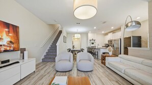 Ein modernes Wohnzimmer mit Treppe, Essbereich und Küche.