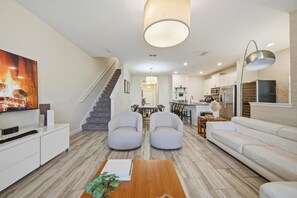 Ein modernes Wohnzimmer mit Treppe, Essbereich und Küche.