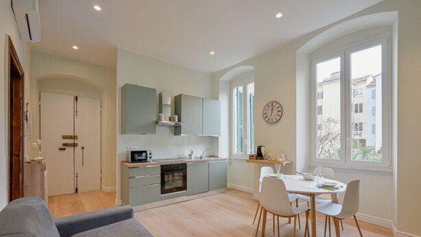 A modern kitchen with a dining area, a sofa, and a view of buildings outside. - GuestHost - Cozy 59mq apartment, perfect for 4 people, located on the first floor of a building without a lift (stairs to access it).The property is located in a well-served residential neighborhood, adjacent to the Historic Center.The Central Station, r (La Spezia)