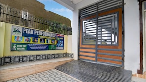 Entrada a una clínica con un letrero que indica Clínica de Fisioterapia Peak Performance, una entrada con rejas y un piso de baldosas.