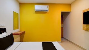 Una habitación de hotel con cama, mesita de noche, espejo, aire acondicionado y televisión.