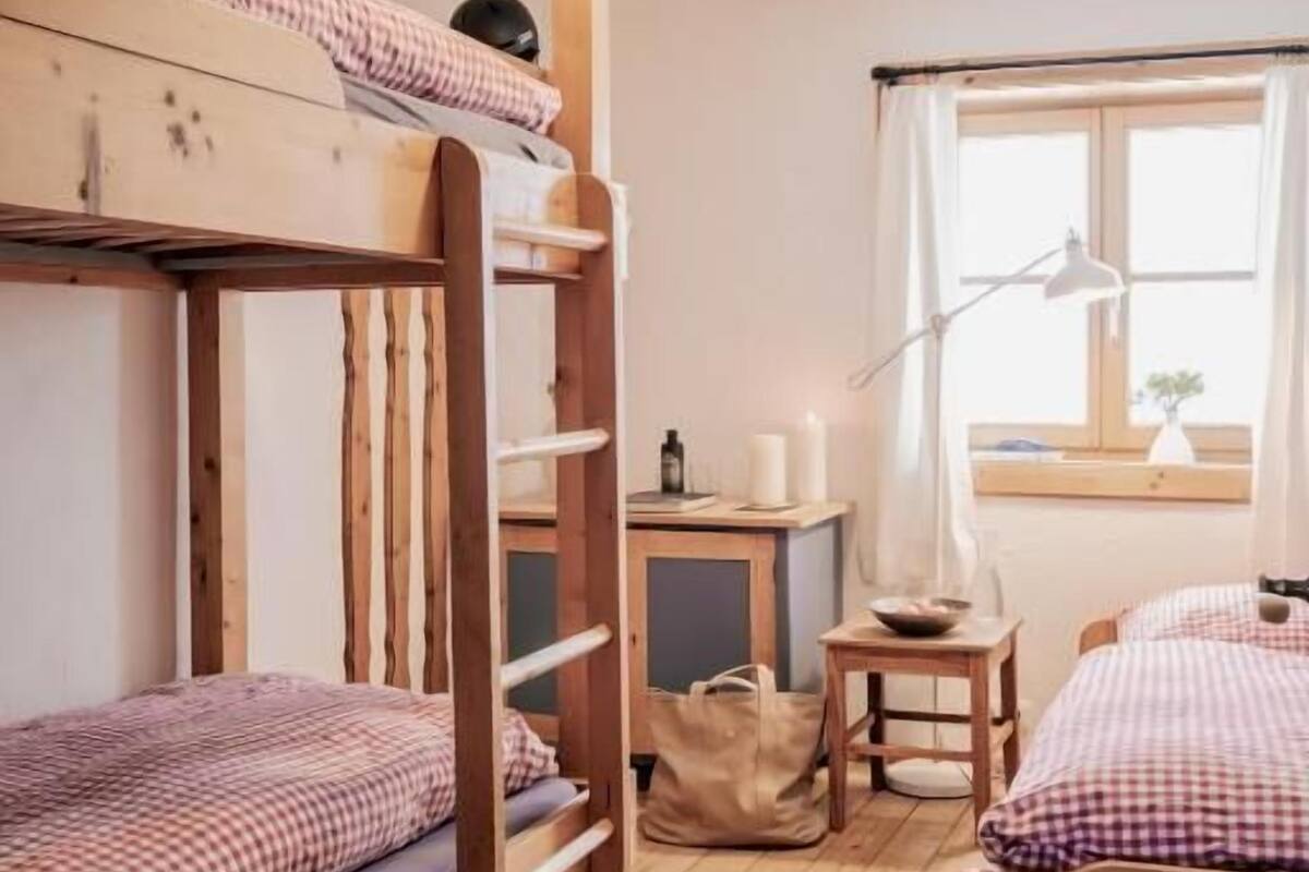 Habitación con literas, escritorio, lámpara y ventana con cortinas.