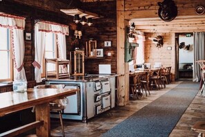 Una cucina rustica con pareti in legno, un'isola centrale e un'area da pranzo con sedie di legno.