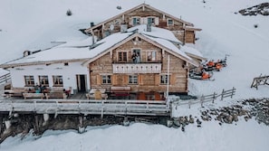 A wooden chalet with a balcony, a ski lift in the background, and a wooden deck in front. - Resterhöhe Berggasthaus & Lodge (Mittersill)