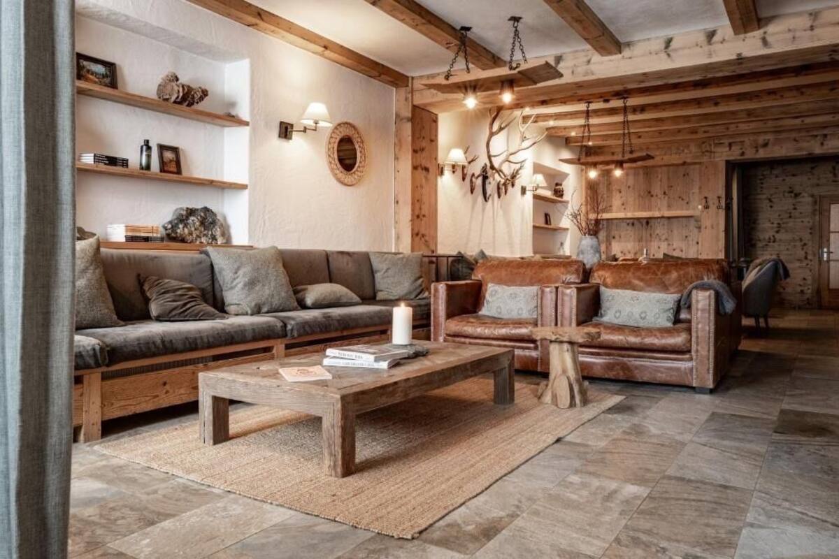 Una sala de estar acogedora con sofá, sillones, una mesa de centro y vigas de madera en el techo.
