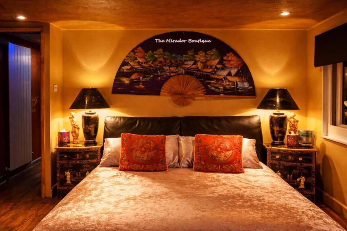 Ein Schlafzimmer mit einem großen Bett, zwei Nachttischen und einem Wandbild mit einer tropischen Szene.