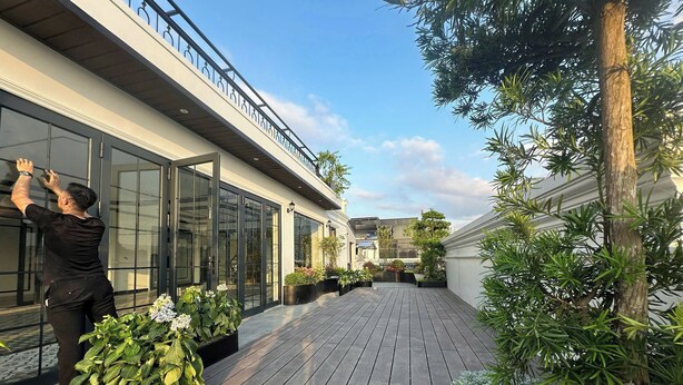A modern building with large glass doors and a wooden deck. - Atlantis Apartment Nguyen Xuan Khoat (Hanoi)