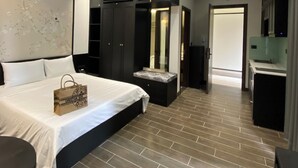 A modern bedroom with a large bed, a vanity, and a walk-in closet. - Atlantis Apartment Nguyen Xuan Khoat (Hanoi)