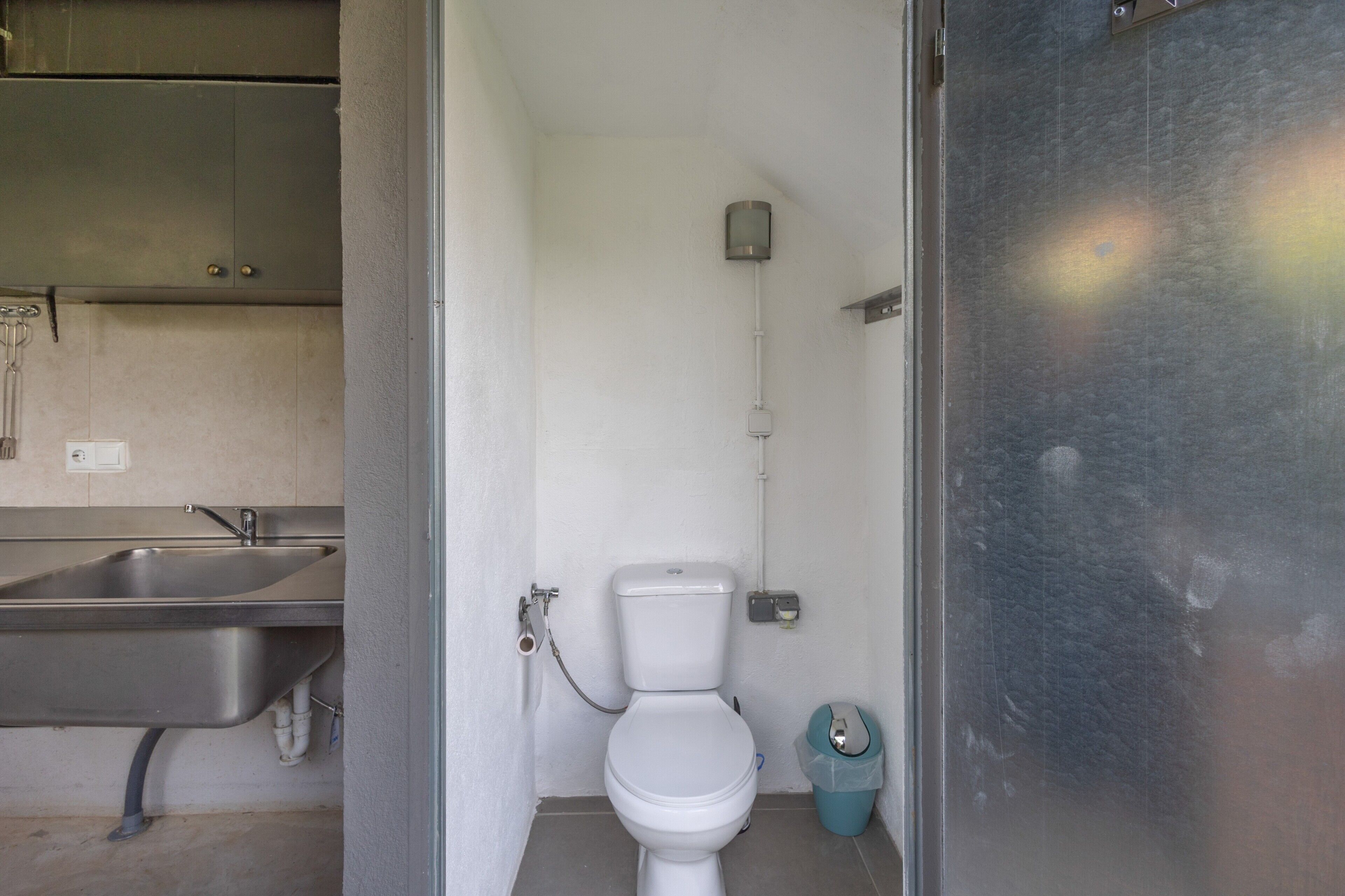 Une petite salle de bain compacte, équipée de toilettes, d’un lavabo et d’une poubelle.