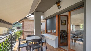 Un balcon avec une table et des chaises, une porte-fenêtre coulissante donnant sur un patio, et un mur en briques.