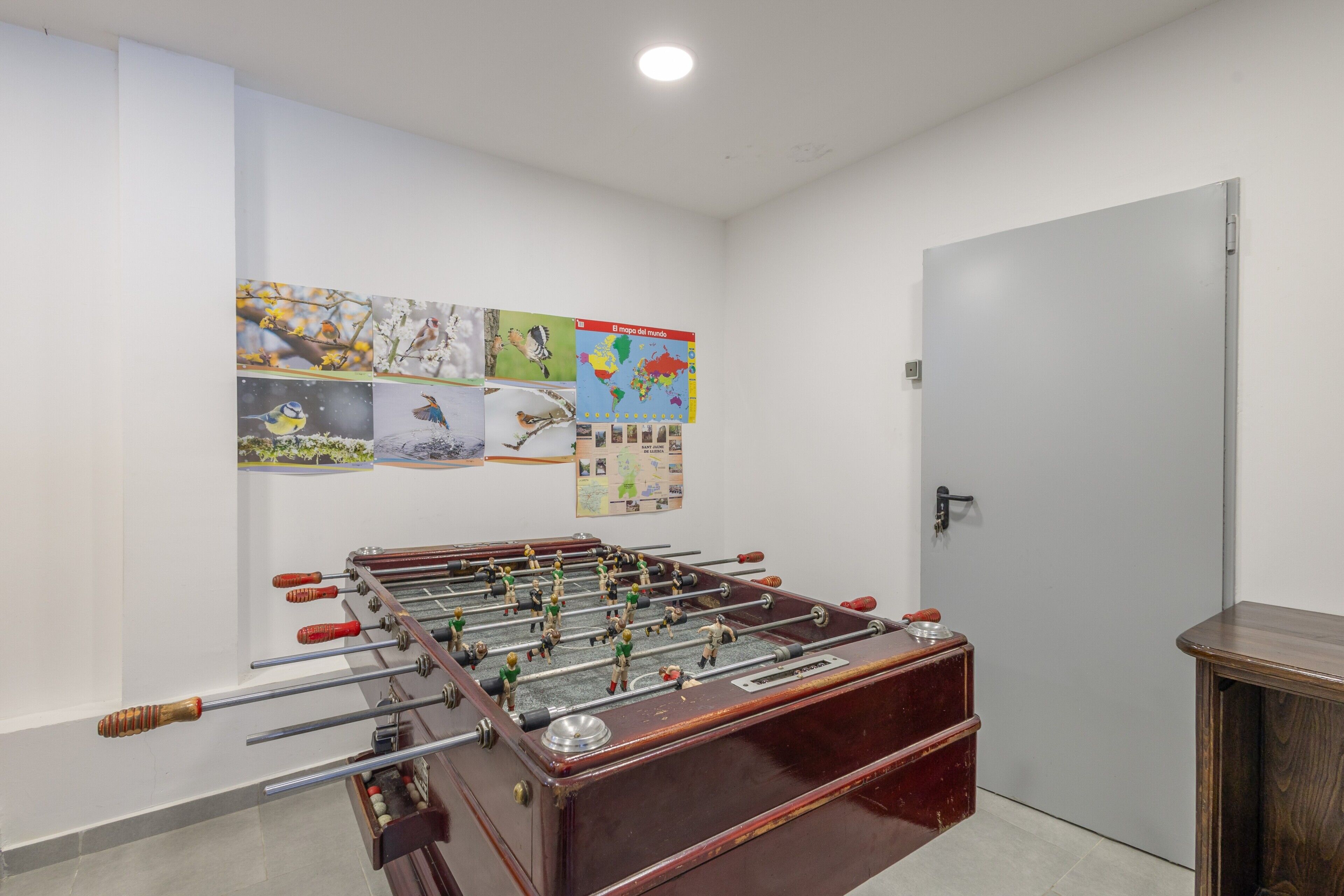 A room with a foosball table, a door, and educational posters on the wall.
