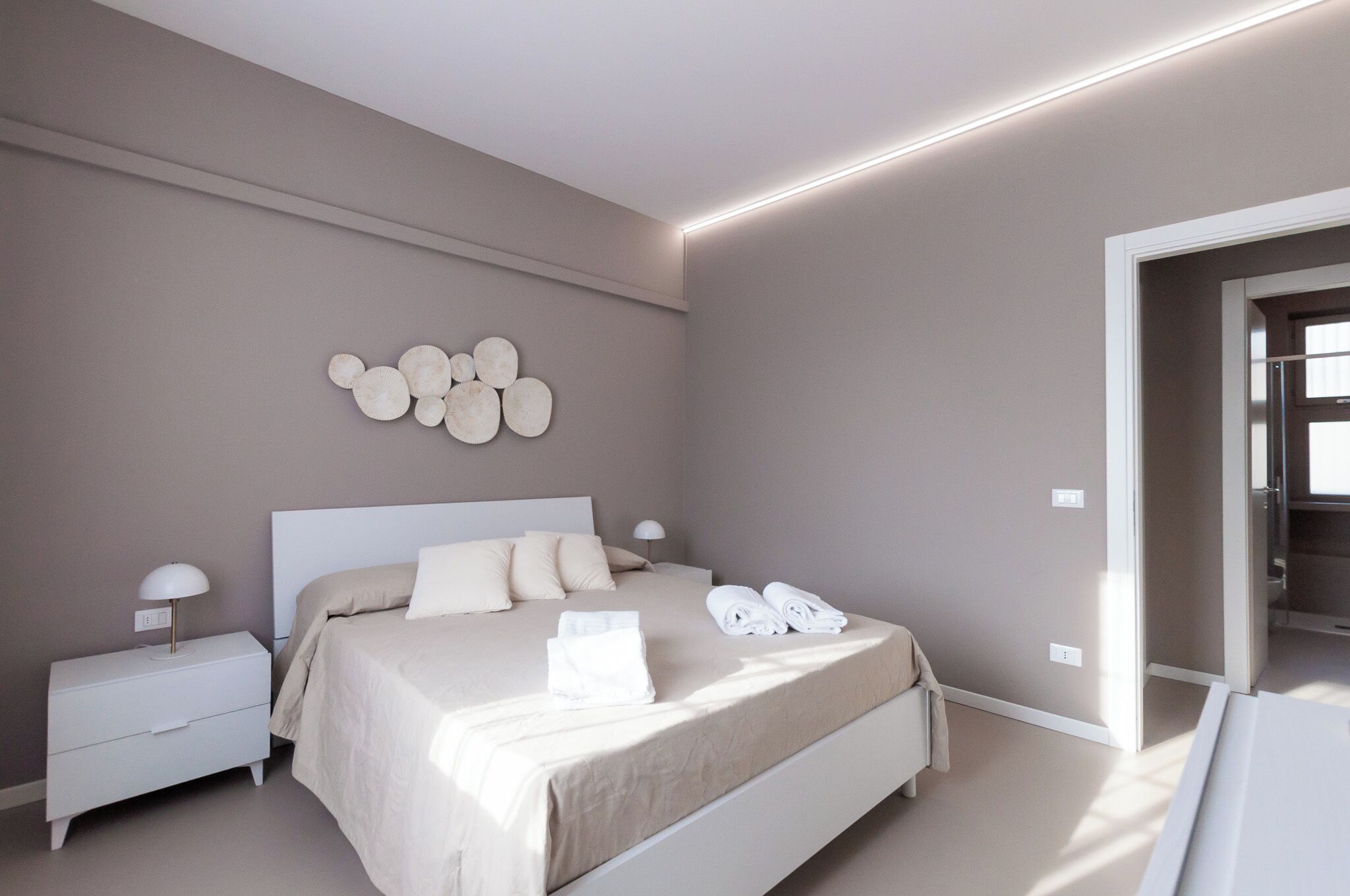 Un dormitorio moderno con una cama grande, mesitas de noche y una obra de arte en la pared.