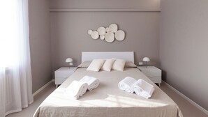 A modern hotel room with a large bed, two bedside tables, and a wall-mounted decorative piece. - Aurora Lights Suite (Desenzano del Garda)