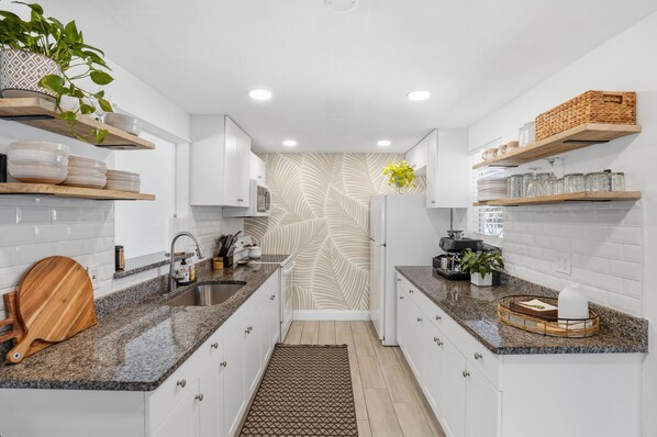 Una cocina moderna con armarios blancos, encimeras de granito y un salpicadero estampado.