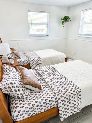 Une chambre avec deux lits simples, une table de chevet avec une lampe et une plante suspendue.