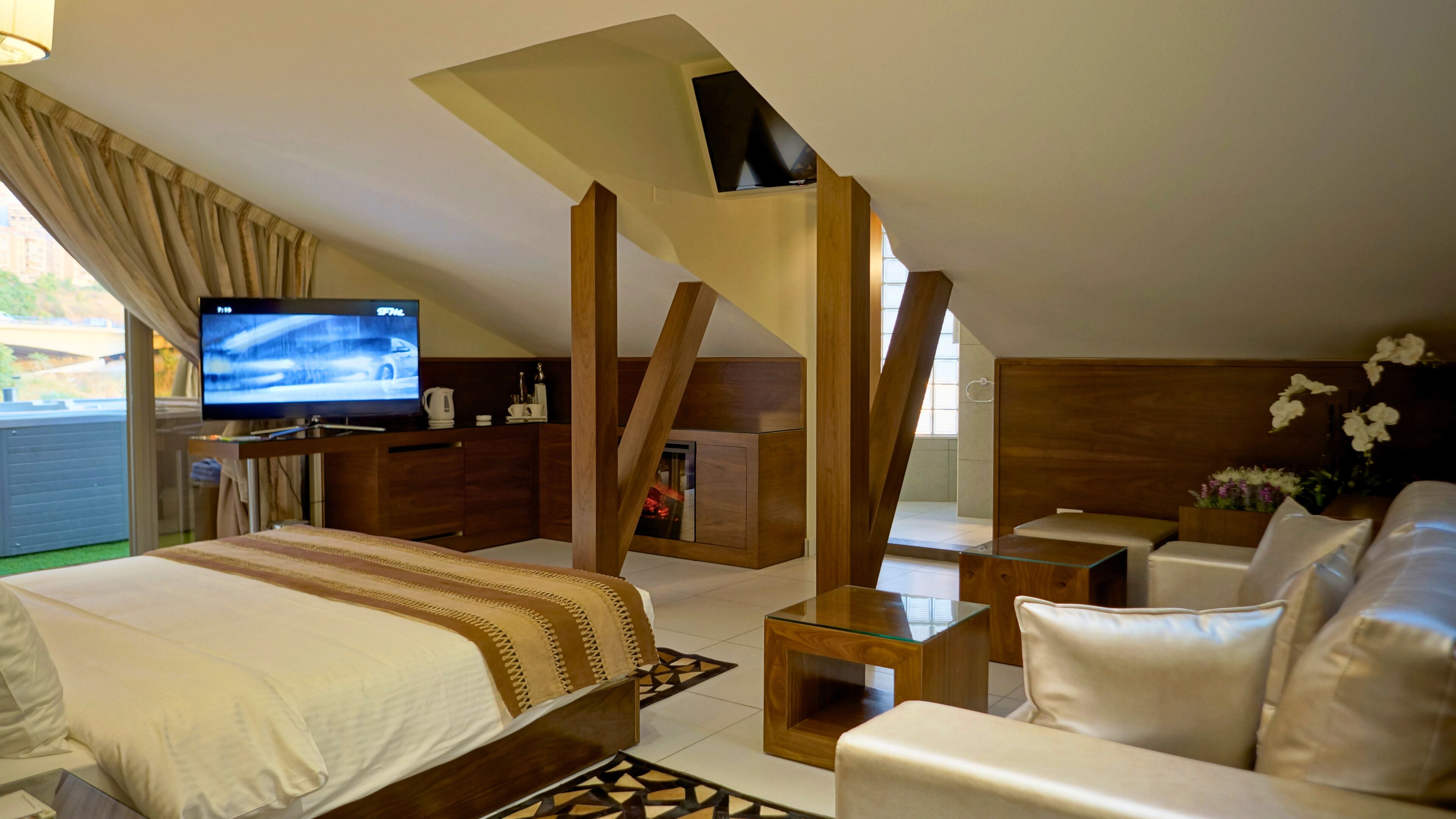 Una habitación de hotel con una cama, televisión, escritorio, sofá y una escalera.