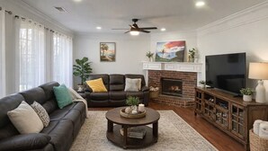 Ein Wohnzimmer mit Kamin, Fernseher und Deckenventilator.