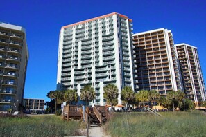A high-rise building with multiple balconies, a wooden deck, and a clear blue sky. - Breaker's Boutique Resort 1857- 2BR/2BA- Pool (Myrtle Beach)
