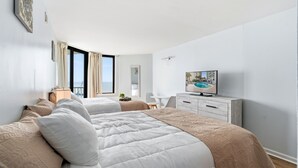 A modern hotel room with two beds, a TV, a desk, and a view of the sea. - Breaker's Boutique Resort 1857- 2BR/2BA- Pool (Myrtle Beach)