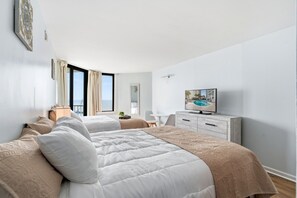 Ein modernes Hotelzimmer mit zwei Betten, einem Fernseher, einem Schreibtisch und Blick auf das Meer.