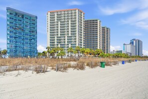 Ein Strandhotel mit mehreren Hochhäusern, einem Sandstrand und etwas Vegetation.