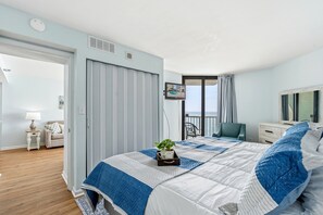 Una habitación de hotel con cama, televisión, balcón y vista al mar.
