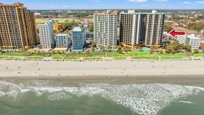 A beachfront hotel with high-rise buildings, a sandy beach, and ocean waves. - Breaker's Boutique Resort 1857- 2BR/2BA- Pool (Myrtle Beach)