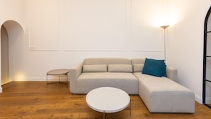 A modern living room with a sectional sofa, a small round table, and a floor lamp. - Trevi Terrace Apartment (Rome)