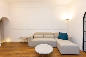 A modern living room with a sectional sofa, a small round table, and a floor lamp. - Trevi Terrace Apartment (Rome)
