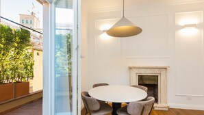 A dining area with a round table and four chairs, a hanging light fixture, and a fireplace. - Trevi Terrace Apartment (Rome)