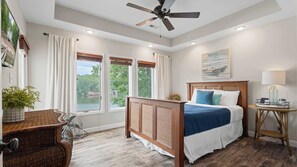 A bedroom with a bed, a ceiling fan, a window with a view, a bedside table, and a lamp. - Mimosa Mornings Home for 12 (Eldon)