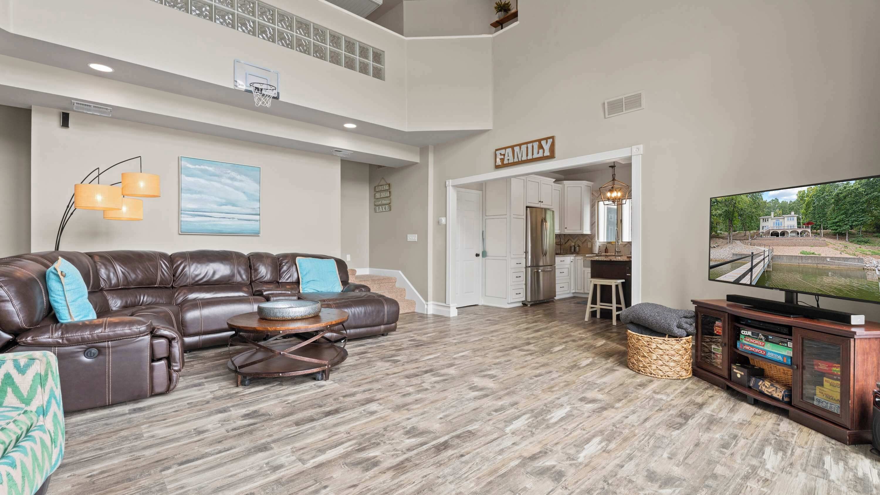 A spacious living room with a leather sectional sofa, a coffee table, and a flat-screen TV.