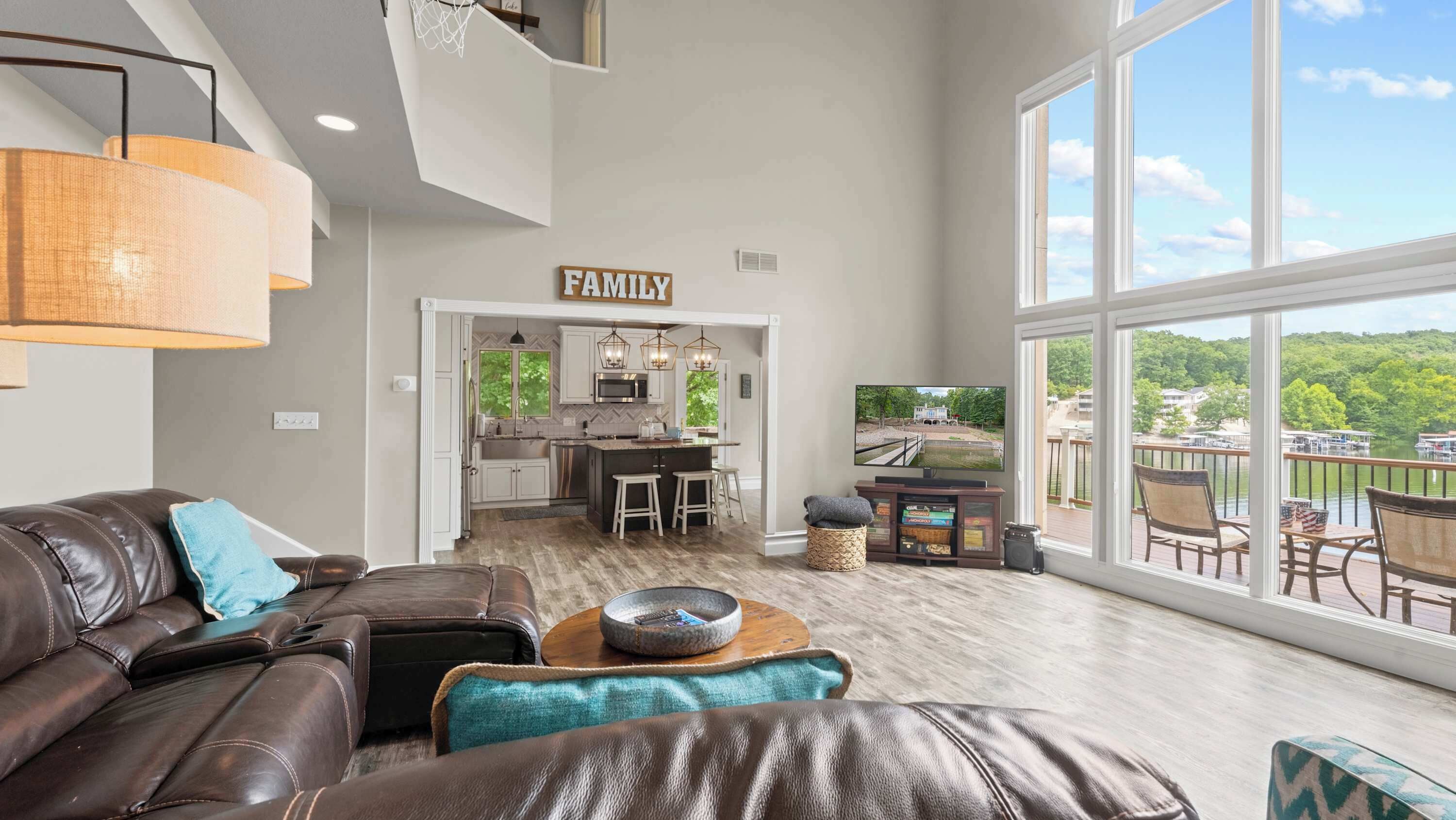 A spacious living room with a leather couch, a coffee table, and a large window overlooking a scenic view.