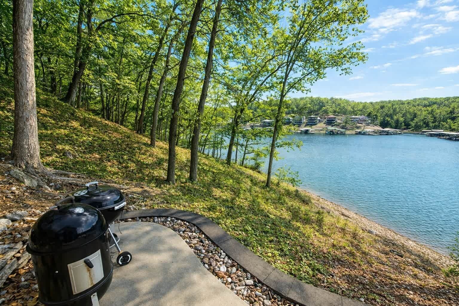 Un sendero junto al lago con una parrilla y un camino pavimentado.