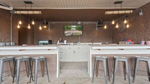 A bar area with a TV screen, stools, and a wooden sign labeled 'BLUES'. - Mimosa Mornings Home for 12 (Eldon)
