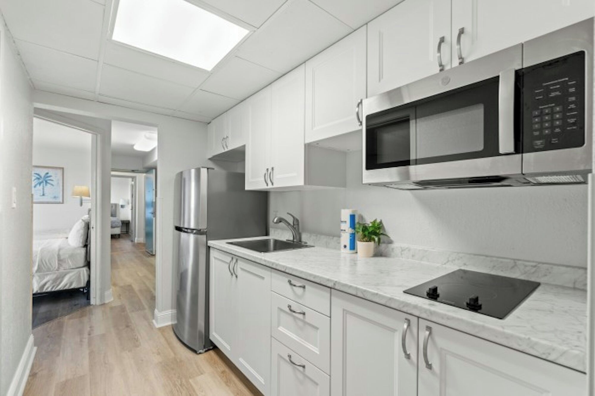 A modern kitchen with white cabinets, stainless steel appliances, and a marble countertop.