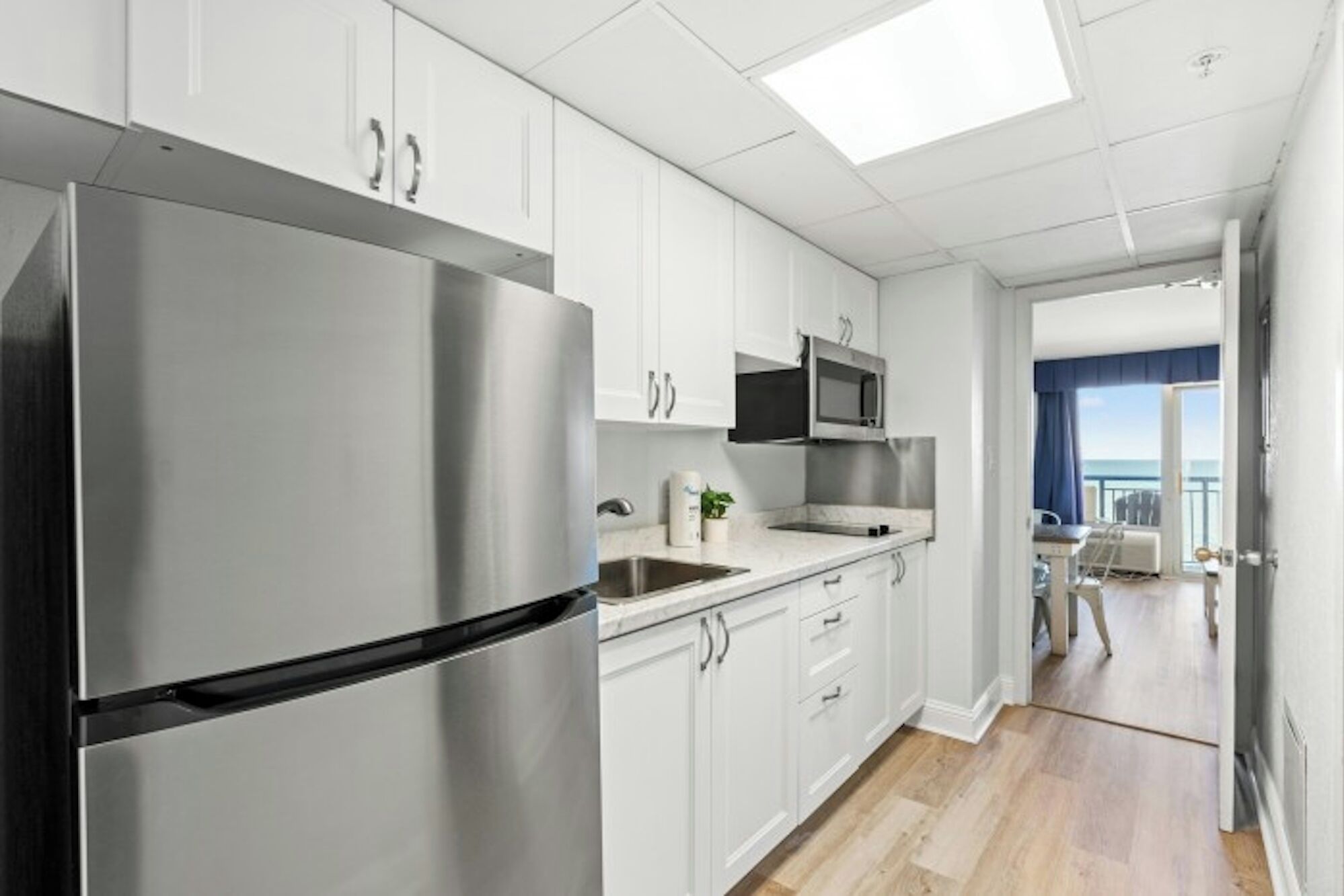A modern kitchen with stainless steel appliances, white cabinetry, and a view to a balcony.