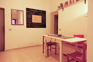 A dining area with a white table, red chairs, and a chalkboard menu on the wall. - Casa Pepe - Three Bedroom Apartment, Sleeps 5 (Pisa)