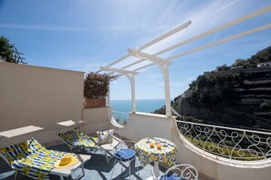 Una terraza con sillones de descanso y una mesa, con vista a un acantilado costero.