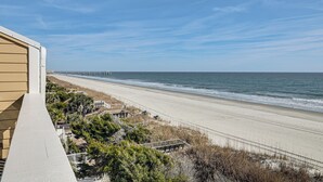 Ein Strand mit einer Holzlattenveranda und einem Pier im Hintergrund.