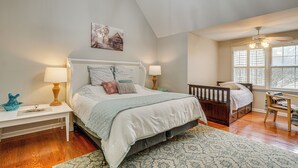 A bedroom with a large bed, two bedside tables, a window with blinds, a ceiling fan, and a wall-mounted picture. - Knoxville Farmhouse Retreat! Easy Access to Town (Knoxville)